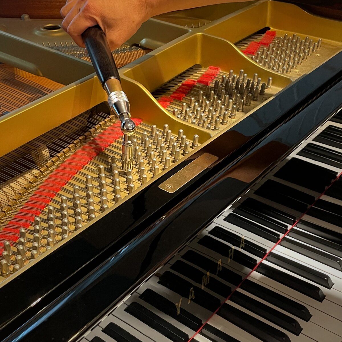 Soundcraft technician tuning a Yamaha grand piano with a tuning hammer