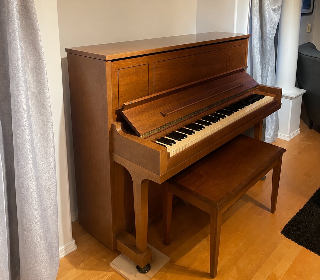 Steinway & Sons upright piano with matching bench in a living room